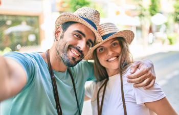 Joyful man and woman wearing straw hats taking a selfie.