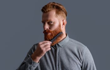 Red-haired bearded man combing his thick beard. Atlanta, GA