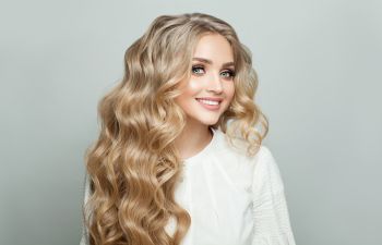 Happy blonde woman with long thick wavy hair.