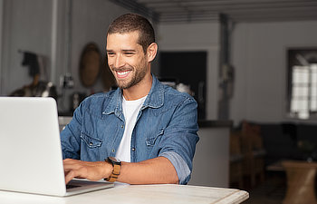 happy young businessman using laptop at home Atlanta, GA