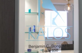 Glass door with Kalos logo, profile silhouette graphic, and contact information for surgery, hair, and spa services under "Benjamin C. Stong, M.D., Suite 850.