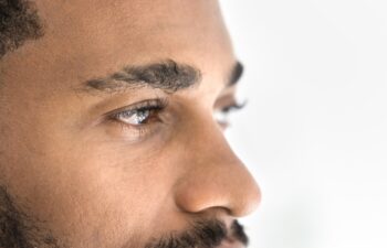 Handsome young African man looking away banner shot. Serious attractive Black guy upper face close up cropped portrait. Male model advertising eyes care, eyesight checkup, vision correction